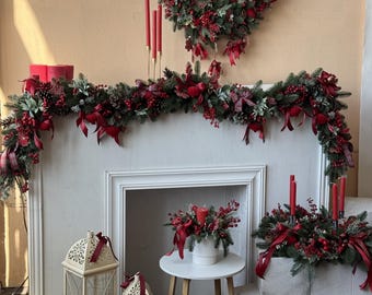 Puede incluir: Una exhibición navideña festiva con una corona, guirnalda y arreglos florales con bayas rojas, lazos y velas. También hay dos faroles blancos con velas y una pequeña mesa blanca con un arreglo floral. La combinación de colores es rojo, verde y blanco.
