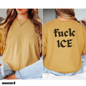 May include: Mustard-colored long-sleeve shirt with the text "fuck ICE" printed in black on the back. The shirt is a solid color and has a relaxed fit. The word "mustard" is printed at the bottom of the image.