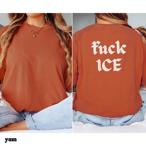 May include: A yam-colored t-shirt with the text "fuck ICE" in white, stylized lettering on the back. The shirt is a solid color and has a relaxed fit. The front of the shirt is plain.