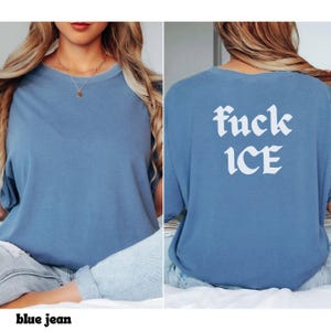 May include: A blue jean colored t-shirt with the text "fuck ICE" in white gothic font on the back. The front of the shirt is plain. The shirt is a crew neck and has short sleeves.