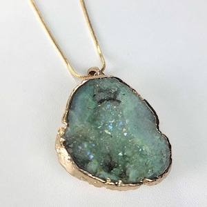 May include: A gold chain necklace with a green agate pendant. The pendant is a slice of agate with a gold rim.