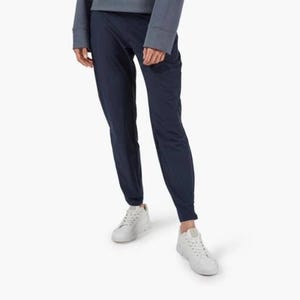 May include: Navy blue joggers with a tapered leg. The pants are paired with a matching top and white sneakers. The outfit is simple and casual, suitable for everyday wear.