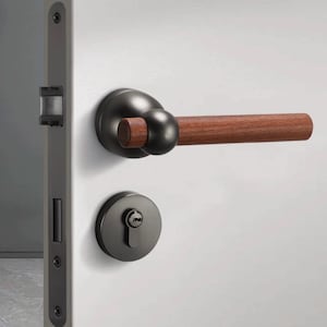 Könnte beinhalten: Ein schwarzer Türgriff mit einem Holzhebel und einem runden Schlüsselloch. Der Griff ist an einer weißen Tür montiert.