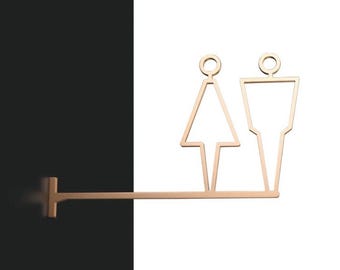 May include: A gold metal sign with a silhouette of a woman and a man. The sign is attached to a black wall with a metal bar.