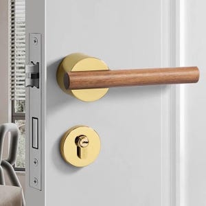 Peut inclure: Une poignée de porte dorée avec un levier en bois. La poignée a une base ronde dorée et un trou de serrure.