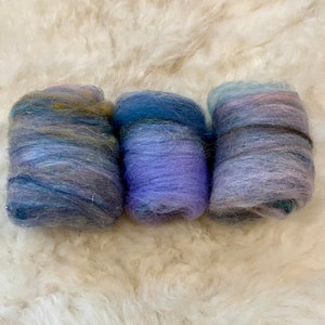May include: Three skeins of hand-dyed yarn in shades of blue, purple, and pink. The yarn is soft and fluffy, and it would be perfect for knitting or crocheting.