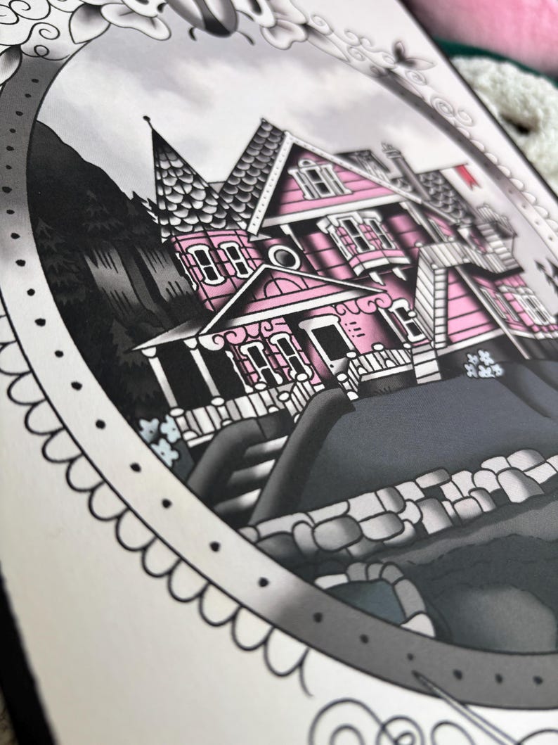 May include: A detailed illustration of a pink Victorian house with a dark gray roof and accents. The artwork is framed with a decorative border and features a gray sky and dark trees in the background. The house has multiple windows and a small red flag.