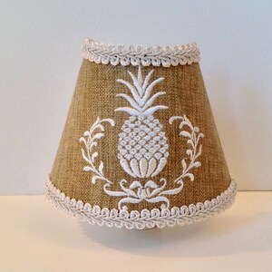 May include: A beige lampshade with a white pineapple design and white trim.