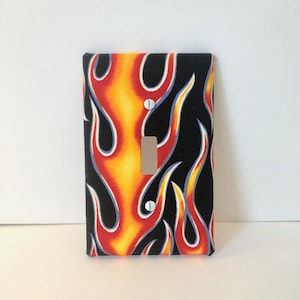May include: A light switch cover with a black background and a flame pattern in red, orange, and yellow.