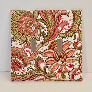 May include: A double light switch cover with a paisley pattern in shades of red, green, and white.