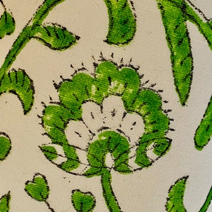 Puede incluir: Una tela blanca con un patr&oacute;n floral verde. El patr&oacute;n presenta una flor grande con un centro blanco y hojas verdes.