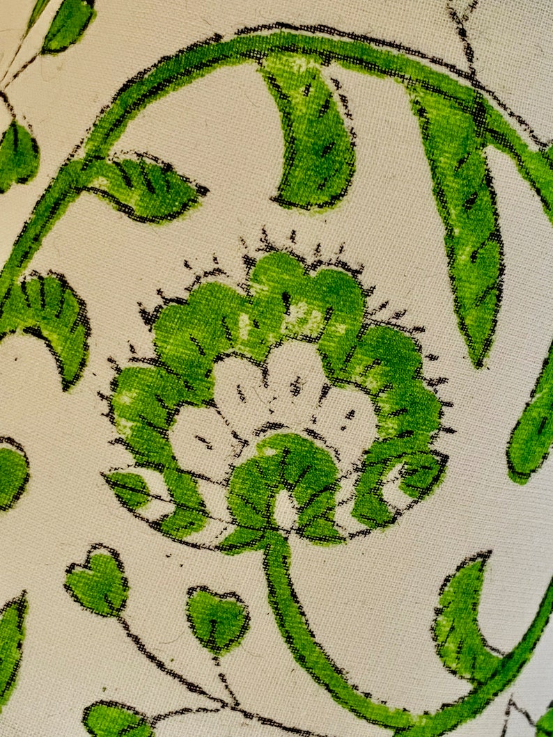 Puede incluir: Una tela blanca con un patr&oacute;n floral verde. El patr&oacute;n presenta una flor grande con un centro blanco y hojas verdes.