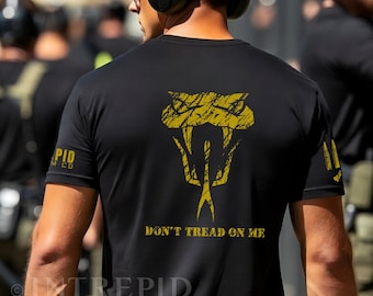 May include: Black t-shirt with a yellow snake graphic and the text "DON'T TREAD ON ME." The shirt also features the text "PID M CO" on the left sleeve and "INTREPID CUSTOM CO" at the bottom.