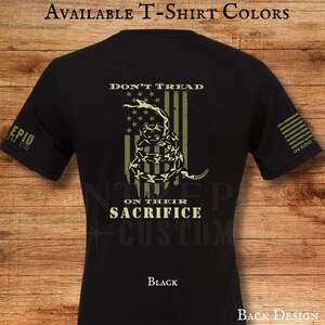 May include: Black t-shirt with a distressed design featuring a coiled snake, stars, and stripes, with the words "DON'T TREAD" and "ON THEIR SACRIFICE". The shirt also has the text "EPID OM CO" on the sleeve.