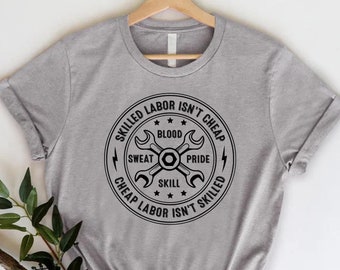 May include: A heather gray t-shirt with a circular black graphic. The graphic features crossed wrenches, stars, and the text "Skilled Labor Isn't Cheap, Sweat, Blood, Pride, Skill, Cheap Labor Isn't Skilled."