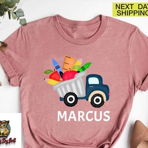 a pink shirt with an image of a truck with apples and carrots in it