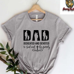 May include: Gray t-shirt with a black graphic that says "DAD DEDICATED AND DEVOTED to God and his family" with a silhouette of a father and children.
