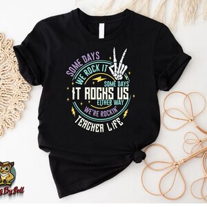 a black t - shirt with a rock and roll design on it