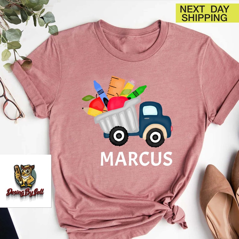 a pink shirt with an image of a truck with apples and carrots in it