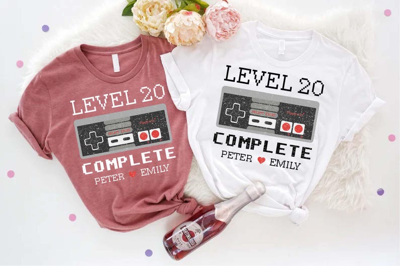 May include: Two t-shirts with a video game controller graphic and the text "Level 20 Complete" with names "Peter" and "Emily".