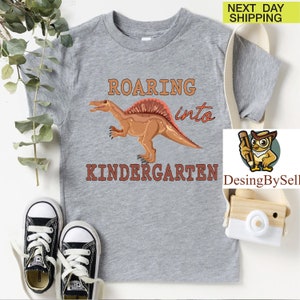 a t - shirt with a dinosaur on it next to a pair of sneakers