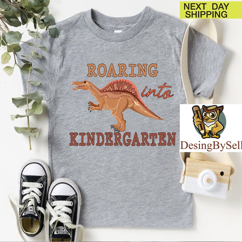 a t - shirt with a dinosaur on it next to a pair of sneakers