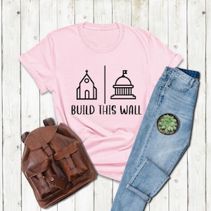 a t - shirt that says build this wall next to a pair of jeans