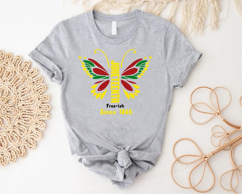 May include: Gray t-shirt with a butterfly design featuring the words "Juneteenth" and "Free-ish Since 1865".