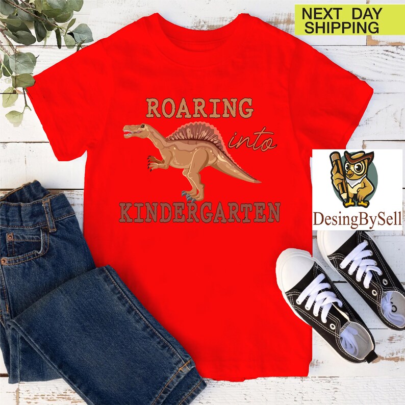 a red t - shirt with a picture of a dinosaur on it