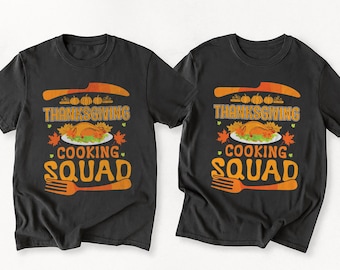 May include: Two black t-shirts featuring a Thanksgiving design. The graphic includes a knife, pumpkins, a roasted turkey, and the words "Thanksgiving Cooking Squad" in orange and white.