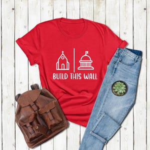 a red shirt that says build this wall next to a pair of jeans and a