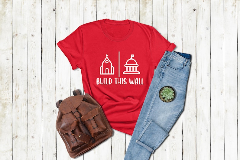 a red shirt that says build this wall next to a pair of jeans and a
