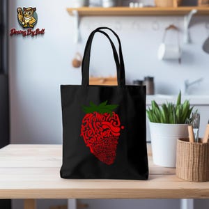 May include: Black tote bag with a red strawberry graphic. The strawberry is made up of the words "Strawberry Fields Forever".