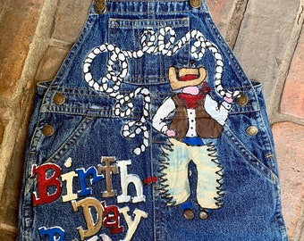 Custom Cowboy Theme Birthday Denim Overalls for Little Boys Featuring hand painted rodeo design, lasso, name and age in red white and blue