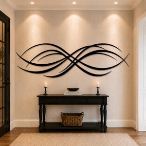 May include: A large black metal wall art piece featuring a series of elongated, sweeping, and intersecting curved lines that form an abstract, horizontal infinity-like shape mounted on a plain, light-coloured interior wall surface.