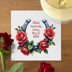 Könnte beinhalten: Ein weißer quadratischer Untersetzer mit einem blauen Hufeisen-Design, roten Rosen und grünen Blättern. Der Text lautet "152nd Kentucky Derby May 2, 2026". Ein Weinglas ist oben rechts zu sehen.