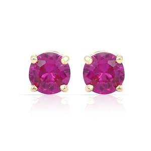 Puede incluir: Un par de pendientes de botón con gemas redondas de color magenta vibrante engastadas en metal dorado. Los pendientes se muestran sobre un fondo blanco, resaltando su color y diseño. Una pieza de joyería clásica.