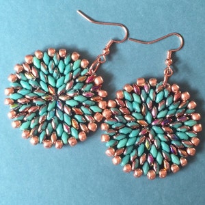 May include: A pair of copper and turquoise beaded earrings. The earrings are round and have a geometric design.