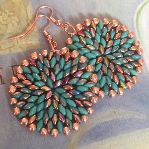 May include: A pair of copper and turquoise beaded earrings. The earrings are round and feature a circular design of turquoise beads with copper beads around the edges.