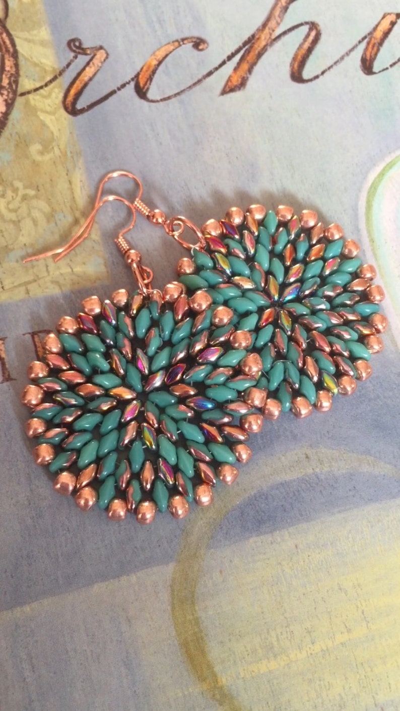 May include: A pair of copper and turquoise beaded earrings. The earrings are round and feature a circular design of turquoise beads with copper beads around the edges.