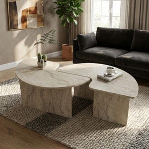 May include: A two-piece coffee table set featuring a beige travertine stone finish with a textured, porous surface. Each table has a curved, semi-circular top supported by a solid, matching stone base, creating a cohesive, organic shape.