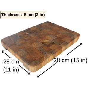 May include: A rectangular wooden butcher block with a mosaic pattern. The block is 15 inches long, 11 inches wide, and 2 inches thick. The wood has a natural brown color and is suitable for food preparation.