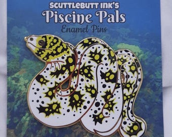 May include: Enamel pin featuring a stylized white and yellow snake with black spots and a gold outline. The pin is on a blue card with the text "SCUTTLEBUTT INK'S Piscine Pals Enamel Pins".