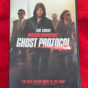 May include: DVD case for the movie "Mission: Impossible - Ghost Protocol" featuring Tom Cruise. The cover shows Cruise in a black hooded jacket with other actors. The title is in large white letters, with the tagline "THE BEST ACTION MOVIE OF THE YEAR!"