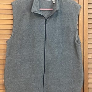 May include: A gray fleece vest with a zipper closure and a collar. The vest has the text "Club ACO" on the front.