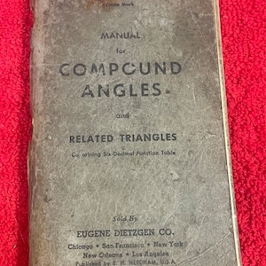 May include: A vintage, gray, paperbound book titled "TR-EASY Manual for Compound Angles and Related Triangles Containing Six-Decimal Function Table" by Eugene Dietzgen Co.