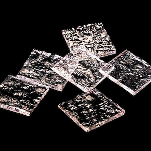 May include: Six clear glass tiles with a textured surface, arranged in a staggered pattern against a black background.