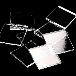 May include: A group of clear glass squares, likely for crafting or mosaic projects.