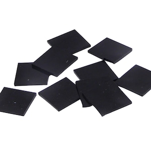 May include: A group of ten black square-shaped rubber pads.