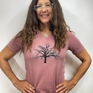 May include: A mauve V-neck t-shirt with a black silhouette of a bare tree printed on the front.